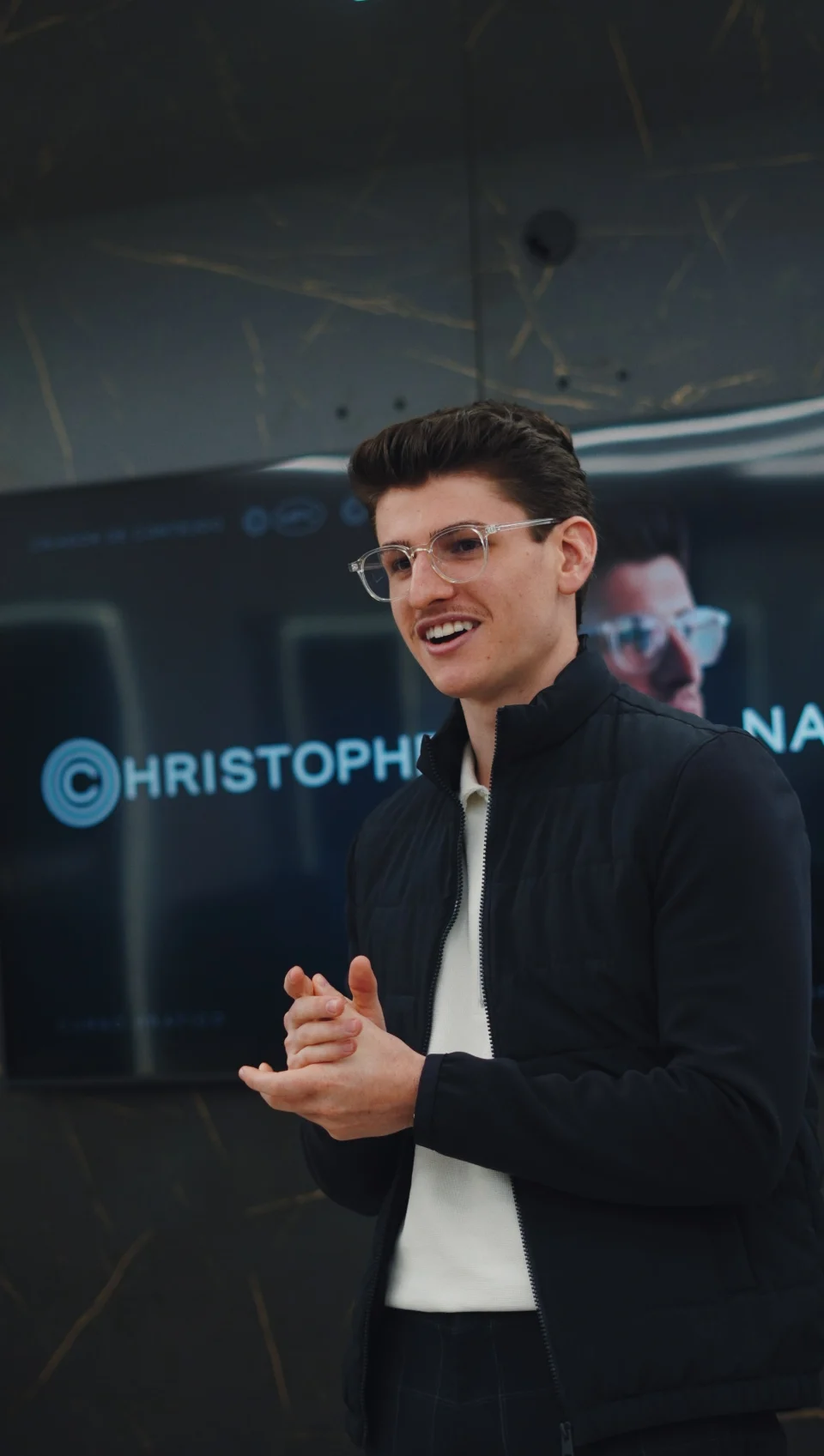 Christopher Naian falando durante um encontro, diante da sua marca