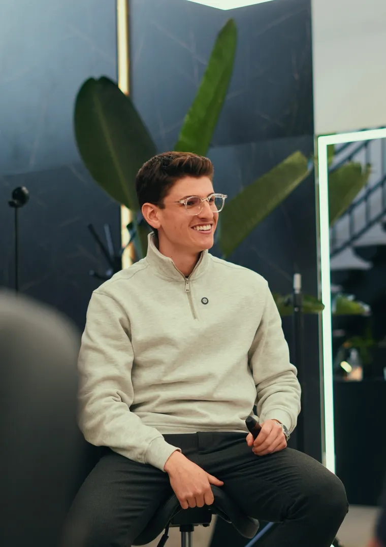 Christopher Naian sentado, sorrindo, durante uma gravação em estúdio.